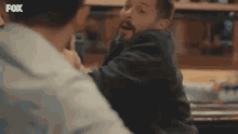 two men are fighting each other in a restaurant .