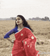 a woman in a red sari is dancing in a field .