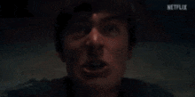 a close up of a man 's face with his mouth open in a dark room .