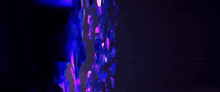 a person in a blue shirt is standing in front of a wall with purple lights .