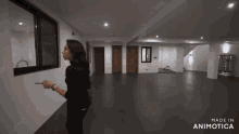 a woman is pointing at a window in an empty room with the words made in animotica on the bottom