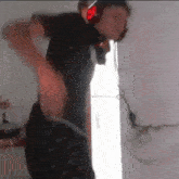 a man wearing headphones and a helmet is standing in front of a refrigerator .