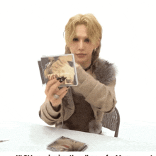 a woman sitting at a table holding a cd that says ' a ' on it