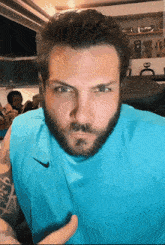 a man with a beard wears a blue nike tank top