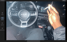 a person smoking a cigarette in a car with a kia logo on the steering wheel
