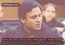 a man is sitting in a classroom talking to a group of people .