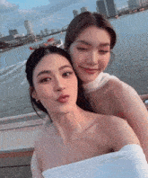 a couple of women posing for a picture with a boat in the background