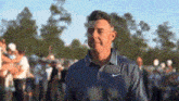 a man wearing a nike shirt is standing in front of a crowd of people .