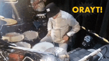 a man is playing drums in front of a sign that says orwyt