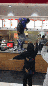a man in a purple vest is standing on a counter in a fast food restaurant