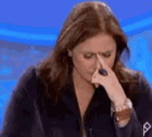 a woman is covering her nose with her hand while looking down .