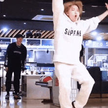 a man wearing a white supreme hoodie is dancing in a bowling alley .