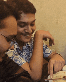 a man in a blue and white shirt is holding another man 's arm