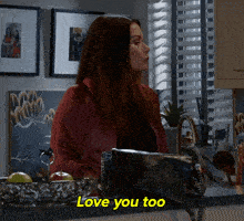 a woman in a red jacket holds a black purse and says love you too