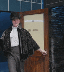a man holding a martini in front of a door that says " ul j bevan "