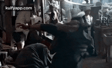 a man is kneeling down in a crowded room while another man stands in the background .