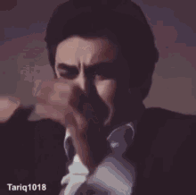 a person covering their face with their hands and the number tariq1018