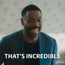 a man in a suit is smiling with the words that 's incredible behind him