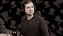 a man wearing headphones is sitting at a table with a bottle of beer in front of him .