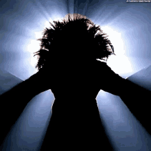 a silhouette of a woman with her arms outstretched in front of the sun