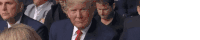 donald trump is sitting in a crowd of people .
