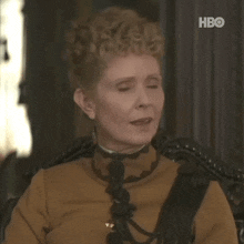 a woman in a brown dress is sitting in a chair making a funny face .