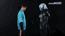 a man wearing a blue shirt with a logo that says ' kamen rider ' on it