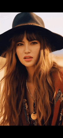 a woman with long hair wearing a black hat and a necklace with a coin on it