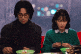 a man and a woman are sitting at a table eating