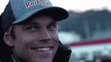 a close up of a man wearing a red bull hat smiling .