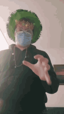 a man wearing a mask and a green hat is making a hand gesture