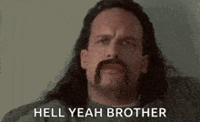 a man with a mustache and long hair is sitting on a couch .