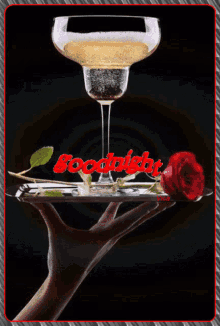 a hand holding a tray with a glass of wine and a red rose with the words goodnight written on it