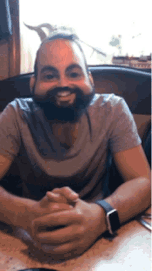 a man with a beard is smiling and wearing a watch
