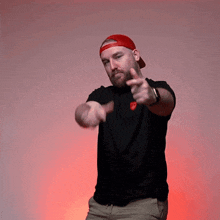a man wearing a black shirt and a red hat is pointing
