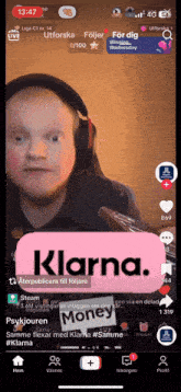 a phone screen shows a man wearing headphones and a klarna logo on it