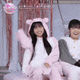 two girls are sitting next to each other and one of them is wearing a pink hoodie