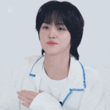 a young man wearing a white jacket with a blue collar is clapping