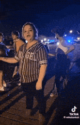a woman in a striped shirt with the word angels on it is standing next to a group of people .