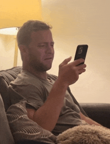 a man sitting on a couch looking at a cell phone