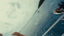 a person is sitting on the edge of a boat in the water .