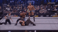 a wrestler is being pinned by another wrestler while a referee watches