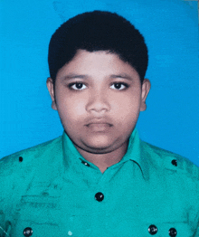 a young boy in a green shirt stands in front of a blue wall
