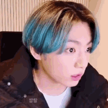 a close up of a person 's face with blue hair and a black jacket .