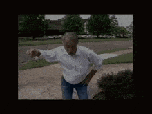 a man in a white shirt and blue jeans is standing on the sidewalk