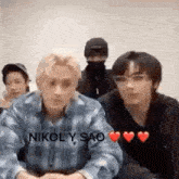 a group of young men are sitting next to each other in a room and looking at the camera .