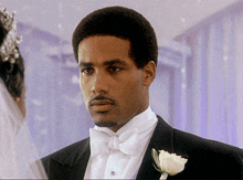 a man in a tuxedo and bow tie stands in front of a woman in a veil