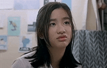 a young girl is making a funny face while sitting in front of a window .