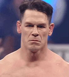 a man without a shirt looks at the camera with a serious look on his face