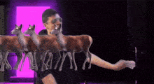 a man is standing in front of a row of deer with a purple background